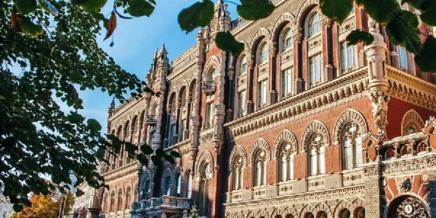Червона цегляна будівля НБУ з арками та декором серед зелених дерев