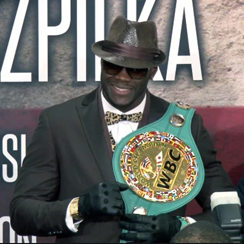Деонтей Уайлдер в шляпе и очках держит пояс WBC